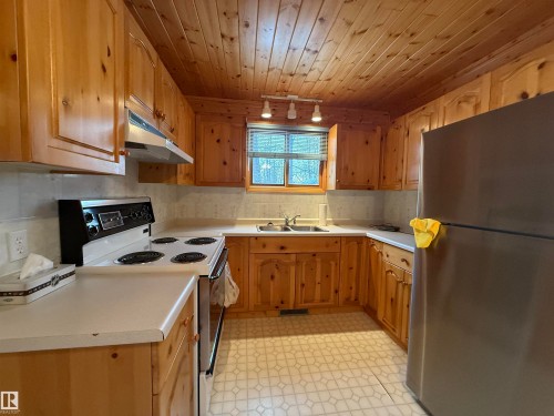 Kitchen with electric range, freestanding refrigerator, light countertops, light floors, and under cabinet range hood - 34 Ella Mae Crescent, Rural Athabasca County, AB - Indoor Photo Showing Kitchen With Double Sink