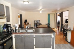 Kitchen with a peninsula, gray cabinetry, electric range, light wood-style flooring, and dark countertops - 