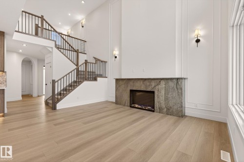 Unfurnished living room with a glass covered fireplace, light wood finished floors, arched walkways, recessed lighting, and a high ceiling - 9 Elwyck Gate, Spruce Grove, AB - Indoor With Fireplace
