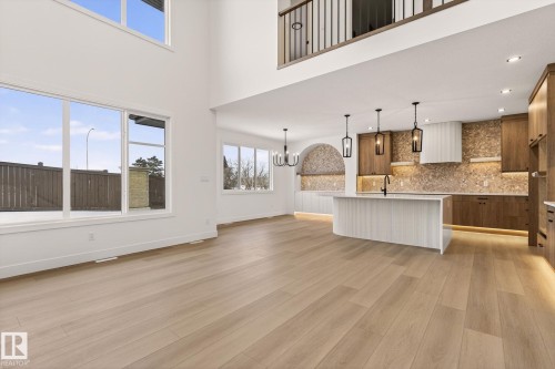Unfurnished living room with light wood-style floors, hanging lights, plenty of natural light, and a high ceiling - 9 Elwyck Gate, Spruce Grove, AB - Indoor Photo Showing Kitchen With Upgraded Kitchen