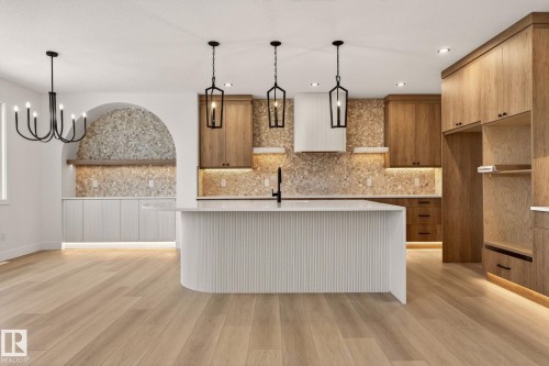 Kitchen with a kitchen island with sink, light stone countertops, wood finish cabinets, modern cabinets, and light wood finished floors - 9 Elwyck Gate, Spruce Grove, AB - Indoor Photo Showing Kitchen With Upgraded Kitchen