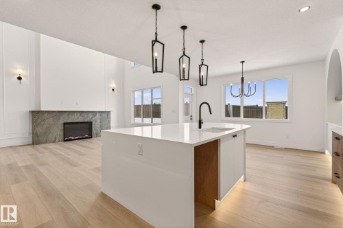 Kitchen featuring light wood-type flooring, pendant lighting, open floor plan, and a high end fireplace - 9 Elwyck Gate, Spruce Grove, AB - Indoor Photo Showing Kitchen