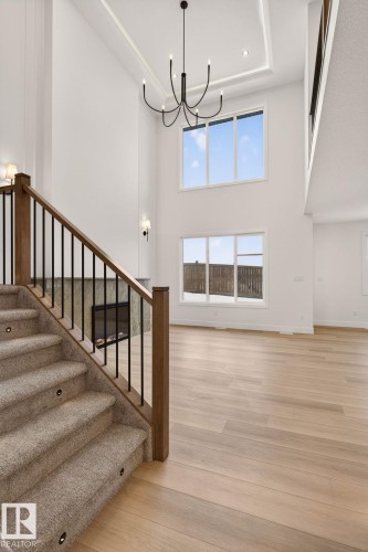 Staircase featuring suspended lighting, a tray ceiling, and wood finished floors - 9 Elwyck Gate, Spruce Grove, AB - Indoor Photo Showing Other Room