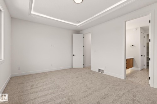 Unfurnished bedroom featuring light colored carpet, a tray ceiling, and ensuite bathroom - 9 Elwyck Gate, Spruce Grove, AB - Indoor Photo Showing Other Room