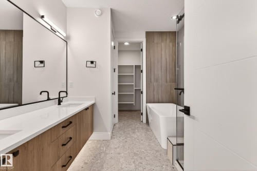 Full bath with a freestanding bath, double vanity, a walk in closet, and dark speckled floor - 9 Elwyck Gate, Spruce Grove, AB - Indoor