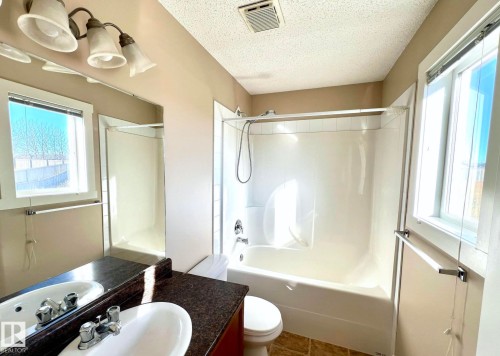 Full bath featuring shower / bath combination, vanity, plenty of natural light, and a textured ceiling - 3705 11 Street, Edmonton, AB - Indoor Photo Showing Bathroom