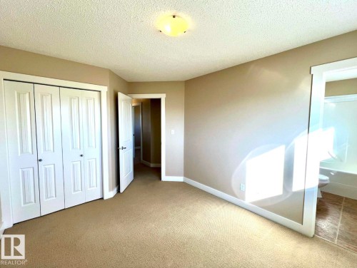 Unfurnished bedroom featuring carpet floors, a closet, and a textured ceiling - 3705 11 Street, Edmonton, AB - Indoor