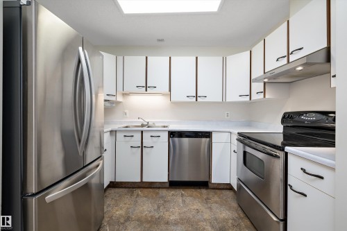 Kitchen with white cabinetry, stainless steel appliances, and light countertops - 218 18012 95 Avenue, Edmonton, AB - Indoor Photo Showing Kitchen With Stainless Steel Kitchen With Double Sink