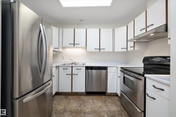 Kitchen with white cabinetry, stainless steel appliances, and light countertops - 