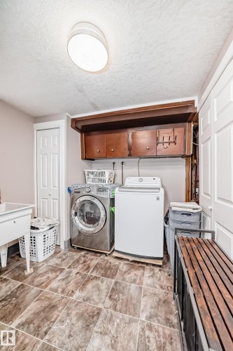 Laundry area with a textured ceiling, separate washer and dryer, and cabinet space - 12203 147 Avenue, Edmonton, AB - Indoor Photo Showing Laundry Room