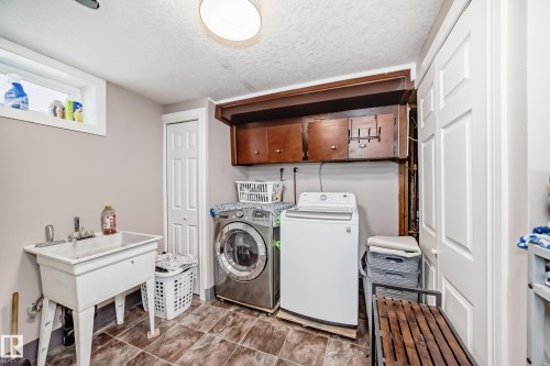 Laundry room featuring a textured ceiling, washing machine and dryer, and cabinet space - 12203 147 Avenue, Edmonton, AB - Indoor Photo Showing Laundry Room