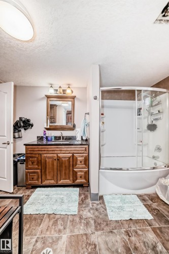 Bathroom featuring vanity, bath / shower combo with glass door, and a textured ceiling - 12203 147 Avenue, Edmonton, AB - Indoor Photo Showing Bathroom