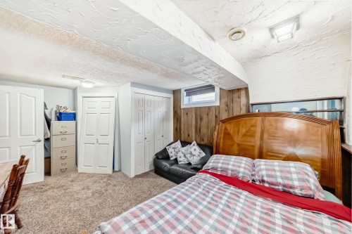 Bedroom featuring a textured ceiling, multiple closets, light carpet, wooden walls, and a textured wall - 12203 147 Avenue, Edmonton, AB - Indoor Photo Showing Bedroom