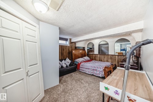 Bedroom with a closet, a textured ceiling, carpet floors, and wooden walls - 12203 147 Avenue, Edmonton, AB - Indoor