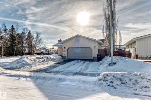 View of front facade featuring an attached garage, stucco siding, driveway, and a chimney - 12203 147 Avenue, Edmonton, AB - Outdoor