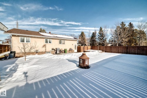 Snow covered rear of property with a fenced backyard, stucco siding, and roof mounted solar panels - 12203 147 Avenue, Edmonton, AB - Outdoor
