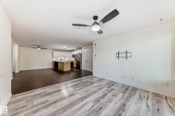 Unfurnished living room featuring a ceiling fan and dark wood-type flooring - 