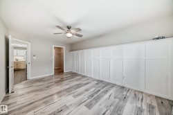 Unfurnished bedroom featuring a spacious closet, light wood finished floors, and ceiling fan - 