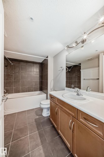 Full bathroom with vanity, shower / tub combination, and dark tile patterned flooring - 125 278 Suder Greens Drive, Edmonton, AB - Indoor Photo Showing Bathroom