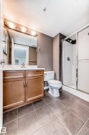Full bath with vanity, a stall shower, light tile patterned floors, and a textured ceiling - 