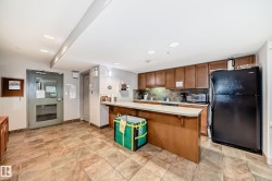 Kitchen featuring wood finish cabinetry, black appliances, light countertops, a kitchen breakfast bar, and a peninsula - 