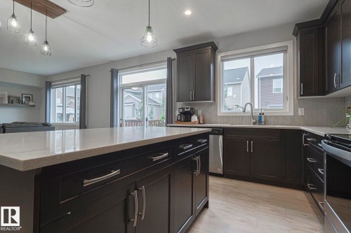 Kitchen featuring decorative backsplash, light stone counters, decorative light fixtures, and open floor plan - 2011 201 Street, Edmonton, AB - Indoor Photo Showing Kitchen With Upgraded Kitchen