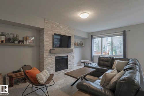 Living room featuring a fireplace, a textured ceiling, and wood finished floors - 2011 201 Street, Edmonton, AB - Indoor Photo Showing Living Room With Fireplace