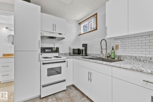 Kitchen with electric range, white cabinetry, under cabinet range hood, a textured ceiling, and stainless steel microwave - 17523 95 Street, Edmonton, AB - Indoor Photo Showing Kitchen