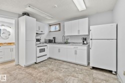 Kitchen featuring white appliances, white cabinets, under cabinet range hood, decorative backsplash, and a textured ceiling - 