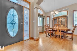 Foyer featuring wood finished floors, a chandelier, high vaulted ceiling, and arched walkways - 