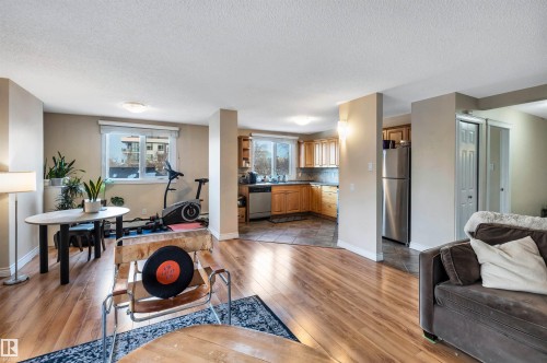 Living area featuring light wood-type flooring and a textured ceiling - 402 9929 113 Street, Edmonton, AB - Indoor Photo Showing Living Room With Fireplace