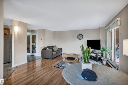 Living room featuring wood finished floors, a baseboard heating unit, and washer / dryer - 402 9929 113 Street, Edmonton, AB - Indoor Photo Showing Living Room