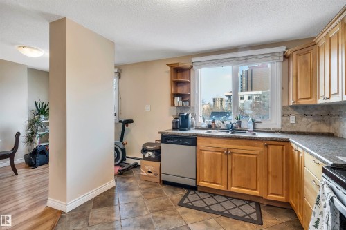 Kitchen featuring stainless steel appliances, tasteful backsplash, open shelves, a textured ceiling, and dark tile patterned flooring - 402 9929 113 Street, Edmonton, AB - Indoor Photo Showing Kitchen With Double Sink