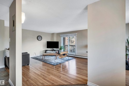 Living area with wood finished floors, a baseboard heating unit, and a textured ceiling - 402 9929 113 Street, Edmonton, AB - Indoor Photo Showing Other Room
