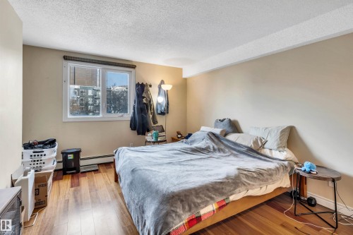 Bedroom with a textured ceiling, hardwood / wood-style flooring, and a baseboard heating unit - 402 9929 113 Street, Edmonton, AB - Indoor Photo Showing Bedroom