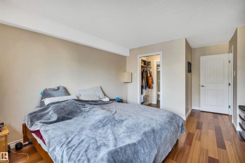 Bedroom featuring a textured ceiling, a walk in closet, and wood finished floors - 402 9929 113 Street, Edmonton, AB - Indoor Photo Showing Bedroom