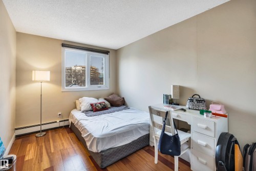 Bedroom with a baseboard radiator, wood finished floors, and a textured ceiling - 402 9929 113 Street, Edmonton, AB - Indoor Photo Showing Bedroom
