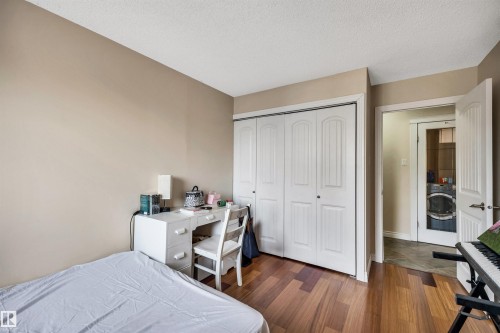 Bedroom featuring dark wood-type flooring, washer / clothes dryer, a closet, and a textured ceiling - 402 9929 113 Street, Edmonton, AB - Indoor Photo Showing Bedroom