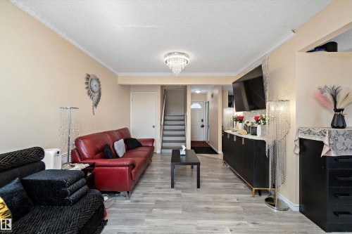 Living room with ornamental molding, a textured ceiling, light wood finished floors, and hanging lights - 127 Cornell Court, Edmonton, AB - Indoor
