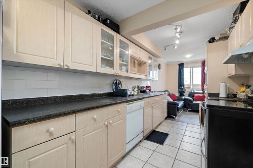 Kitchen with dark countertops, glass insert cabinets, electric range, a textured ceiling, and white dishwasher - 127 Cornell Court, Edmonton, AB - Indoor Photo Showing Kitchen