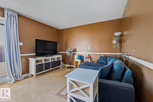 Living area with a textured ceiling and light tile patterned floors - 18307 66 Avenue, Edmonton, AB - Indoor
