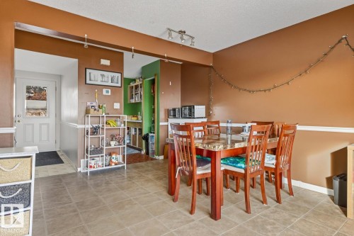 Dining space with a textured ceiling, light tile patterned floors, and rail lighting - 18307 66 Avenue, Edmonton, AB - Indoor Photo Showing Dining Room