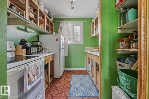 Kitchen featuring white electric stove, a textured ceiling, and light countertops - 18307 66 Avenue, Edmonton, AB - Indoor