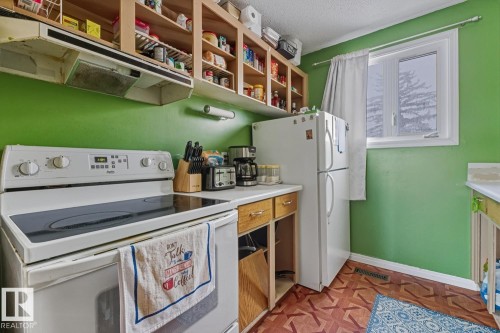 Kitchen with white appliances, extractor fan, light countertops, a textured ceiling, and parquet flooring - 18307 66 Avenue, Edmonton, AB - Indoor Photo Showing Laundry Room