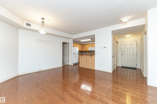 Unfurnished living room featuring a textured ceiling and dark wood-style flooring - 112 260 Sturgeon Road, St. Albert, AB - Indoor