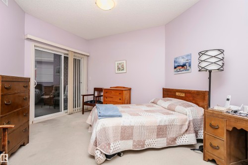 Bedroom with carpet flooring, access to exterior, and a textured ceiling - 112 260 Sturgeon Road, St. Albert, AB - Indoor Photo Showing Bedroom