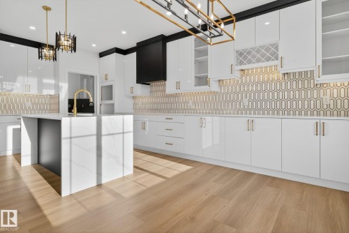 Kitchen with white cabinets, light stone counters, decorative backsplash, light wood finished floors, and modern cabinets - 3508 6 Street, Edmonton, AB - Indoor Photo Showing Kitchen With Upgraded Kitchen