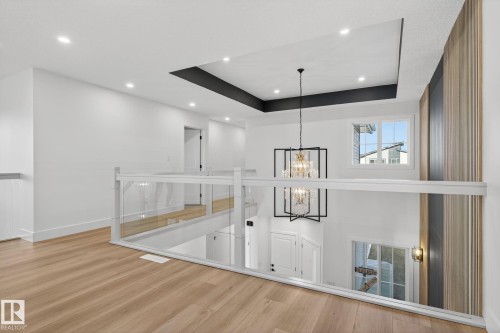 Unfurnished living room with a raised ceiling, a chandelier, and light wood-style floors - 3508 6 Street, Edmonton, AB - Indoor Photo Showing Other Room