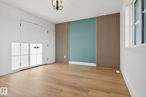 Unfurnished room with wood finished floors, an accent wall, and hanging lights - 3508 6 Street, Edmonton, AB - Indoor Photo Showing Other Room