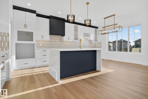 Two tone kitchen with pendant lighting, a kitchen island, light wood-style floors, two tone cabinetry, and modern cabinets - 3508 6 Street, Edmonton, AB - Indoor Photo Showing Kitchen